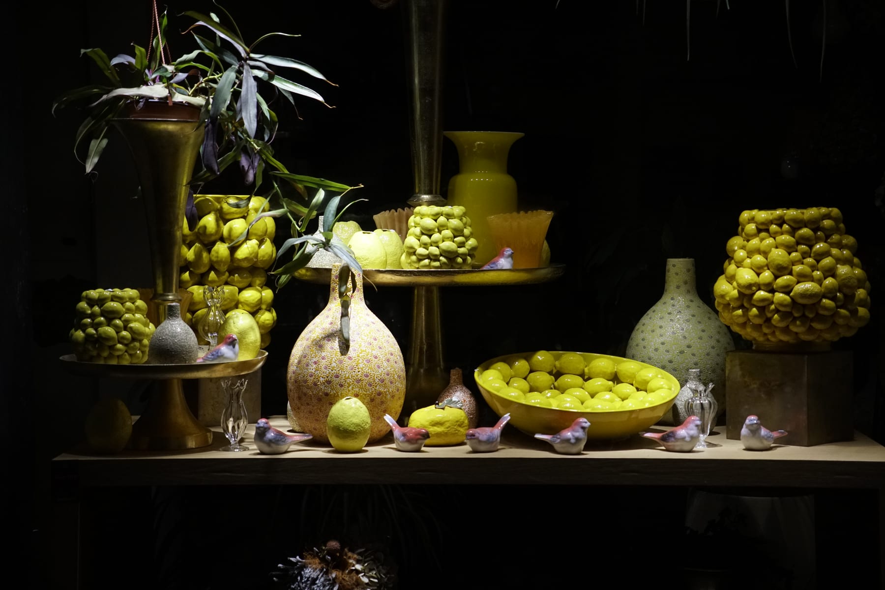 Lemon vases and porcelain birds in a dark shop window